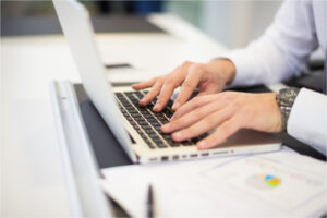 Mains qui tappent écrivent sur clavier de laptop ordinateur portable documents en ligne numérisation