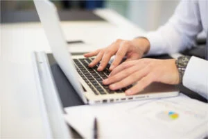 Mains qui tappent écrivent sur clavier de laptop ordinateur portable documents en ligne numérisation