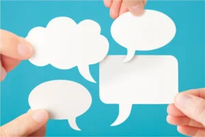 Bulles de dialogue tenues par des mains devant un fond bleu